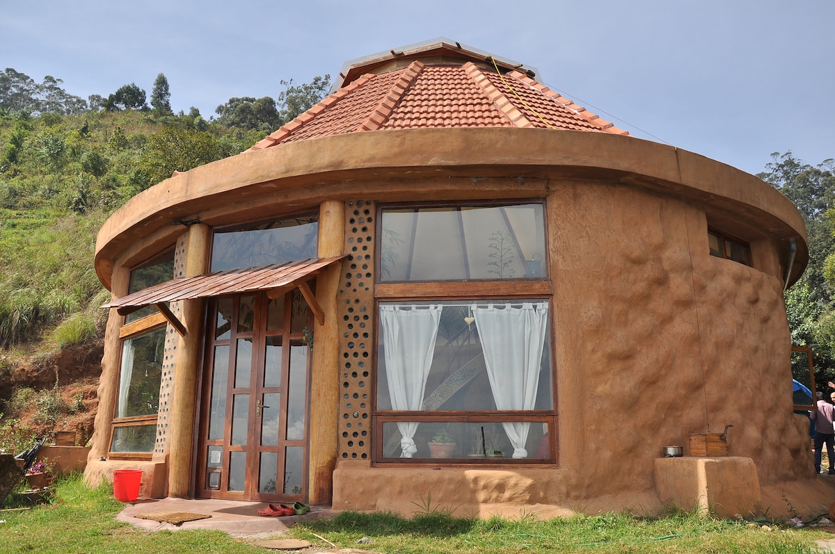 The round earthship exterior, hand-built with earth walls, bottle-glass windows and a tiled roof